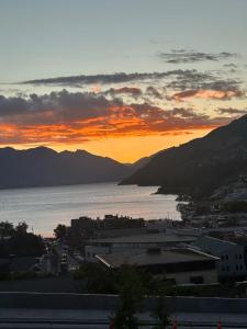 a sunset over a city with the ocean and mountains at Stunning Lake Views in Queenstown
