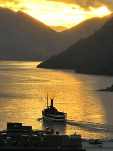 a boat in a body of water at sunset at Stunning Lake Views in Queenstown