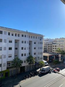 un gran edificio blanco en una calle de la ciudad con palmeras en Appartement lumineux à 5 minutes de la gare, en Casablanca