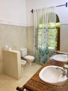 a bathroom with a sink and a toilet and a window at Casa Madro in Malindi