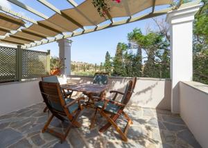 a table and chairs on a patio with a pergola at Saint Louis in Andros