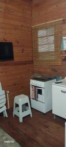 a kitchen with a stove and a stool at recanto de pepe 1 in Santa Vitória do Palmar