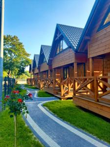 a row of wooden cottages with flowers on a path at Osada Międzywodzie in Międzywodzie