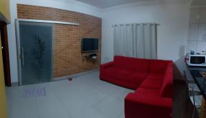 ein Wohnzimmer mit einem roten Sofa und einer Ziegelwand in der Unterkunft Cantinho Abençoado in Pirenópolis