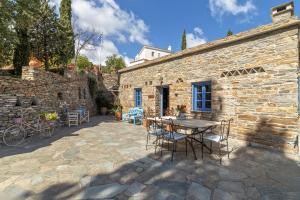a patio with a table and chairs in front of a stone building at Saint Louis in Andros
