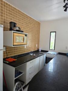 a kitchen with a sink and a microwave at Cantinho da costeira in Bombinhas