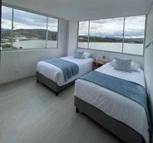 a bedroom with two beds and a large window at Exclusivo apartamento con vista al lago Sochagota in Paipa +32 photos