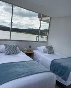 two beds on a boat with a view of the water at Exclusivo apartamento con vista al lago Sochagota in Paipa