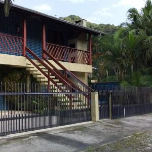 a fence in front of a house with a staircase at Cantinho da costeira in Bombinhas