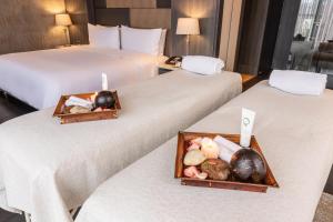 Dos camas en una habitación de hotel con platos de comida. en GHL Bioxury Hotel, en Bogotá 49 fotos más
