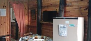 a refrigerator in a room with a table and a television at Recanto do pepe in Chuí