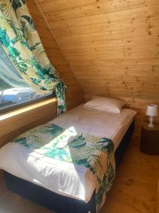 a small bed in a wooden room with a window at Osada Międzywodzie in Międzywodzie