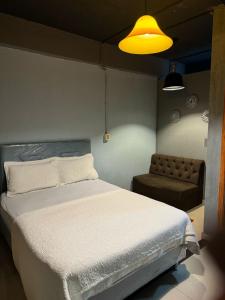 a bedroom with a white bed and a chair at Los Monges Aparthotel in Ciudad del Este