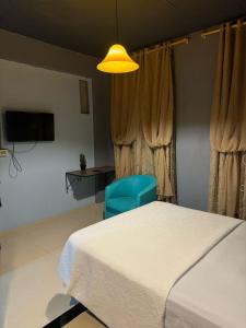 a bedroom with a bed and a blue chair at Los Monges Aparthotel in Ciudad del Este