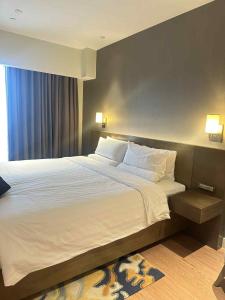 een slaapkamer met een groot bed met witte lakens en kussens bij RBR Lux at Novotel Manila Hotel Residences Acqua in Manilla +26 foto's