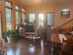 Un comedor con mesas y sillas y ventanas. en Bed and breakfast suite at the Wooded Retreat, en Pine City