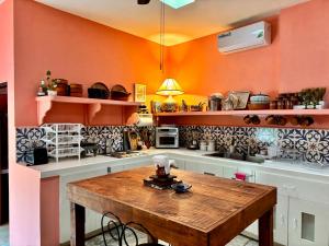 a kitchen with orange walls and a wooden table at Casa Arcana Boutique in Mérida