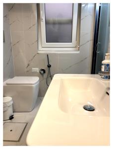 a bathroom with a sink and a toilet and a window at Anfitrite Suite Room in Pozzallo