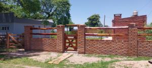 een bakstenen hek met een hek voor een gebouw bij Quincho Gala in El Cadillal