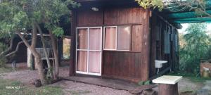 a small wooden house with a window and a bench at Cabañas Recanto do pepe in Santa Vitória do Palmar