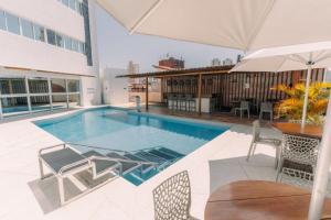 a swimming pool with chairs and an umbrella on a building at Bali Mar Hotel in Natal
