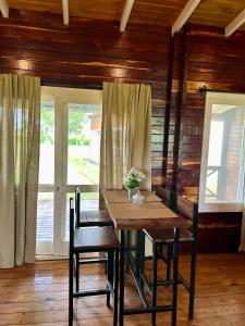 a wooden table and chairs in a room with windows at Lomas Del Delta in Esquina