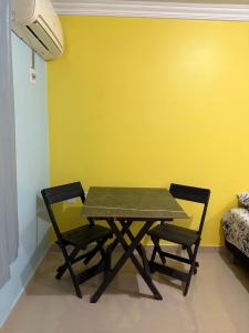 une table et des chaises dans une pièce dotée d'un mur jaune dans l'établissement Quarto privado próximo ao centro, à Manaus