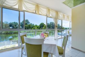a dining room with a table and chairs and windows at Perla Royal Hotel - All Inclusive in Primorsko