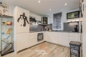 Una cocina con gabinetes blancos y un refrigerador. en The Avengers House, en Magny-le-Hongre