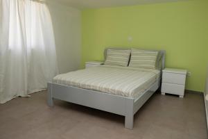 a bed in a room with green walls and a bedskirtspectspectspectspects at Quarto com Vista para a Cidade in Ribeira Grande