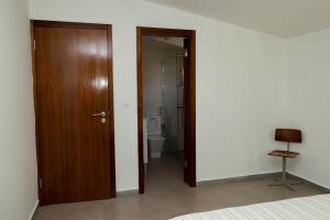 a room with a wooden door and a toilet at Quarto com Vista para a Cidade in Ribeira Grande
