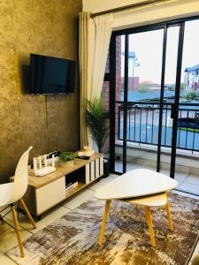 a living room with a tv and a table and chairs at Apartment at the Blyde in Pretoria +16 photos