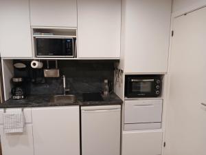 a white kitchen with a sink and a microwave at Cozy Cottage Near the Skjern River in Tarm +7 photos