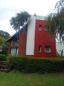 ein rotes Haus mit Palmen davor in der Unterkunft casa Sierras in Sierra de los Padres