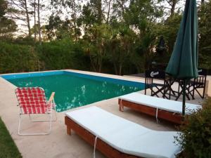 einen Pool mit 2 Stühlen, einem Tisch und einem Sonnenschirm in der Unterkunft casa Sierras in Sierra de los Padres