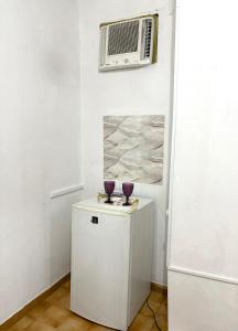 Una habitación con un calentador y dos vasos morados sobre un armario. en Quarto privado no centro 313, en Manaus