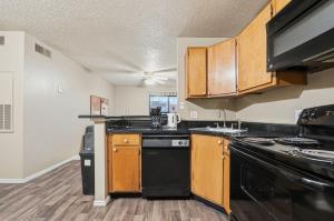 una cocina con electrodomésticos negros y armarios de madera en District West Apartments Your Space To Settle In, en Doud