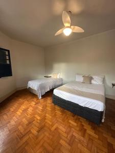 a bedroom with two beds and a ceiling fan at Oxx Quarto Rio in Congonhas