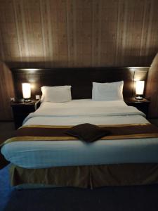 a large bed in a hotel room with two lamps at اصيل الفاخره المخدومه in Taif +12 photos