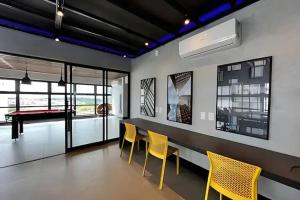 a dining room with yellow chairs and a pool table at Estúdio completo e charmoso in Marília