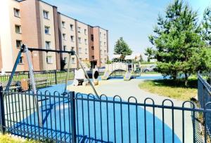 een speeltuin met een schommel voor een gebouw bij M&M Apartment I SELF CHECK-IN near Panevezys in Velžys