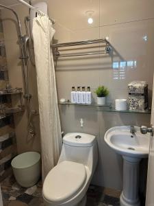 a bathroom with a toilet and a sink at Cozy Modern Apartment Staycation Spot in Tarlac