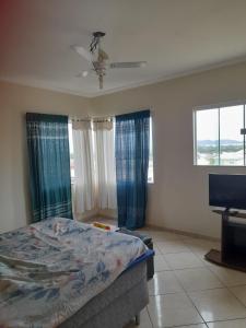 カボ・フリオにあるCasa para temporada em Cabo frioのベッドとテレビと窓のある寝室