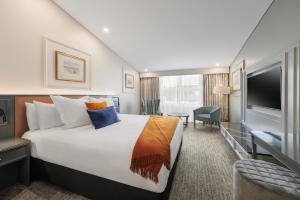 a hotel room with a large bed and a television at Millennium Hotel Queenstown in Queenstown