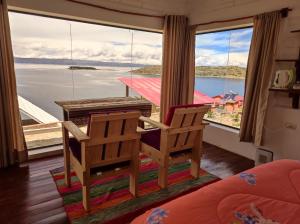 a room with two chairs and a table and a large window at Ecolodge ILLAMPU in Comunidad Challapampa