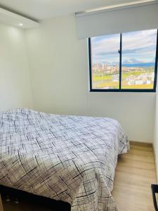 a bedroom with a bed and a large window at Apartamento completo cómodo con vista y todo cerca CC VIVA in Tunja