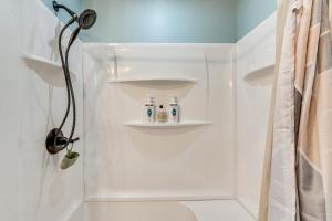 a bathroom with a shower with three bottles on shelves at Walk to Lagoon Saloon! Chic Home on Nugents Canal in Lacarne +21 photos