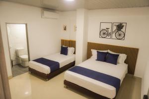 ein Schlafzimmer mit 2 Betten und ein Fahrrad an der Wand in der Unterkunft Hotel Gama Cartagena in Cartagena de Indias