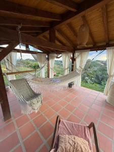 a room with a hammock and a chair on a porch at Encantadora finca en el corazón de Marinilla con vistas únicas y ubicación privilegiada in Marinilla +28 photos