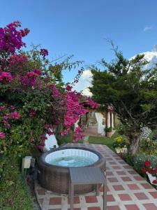 a hot tub in a garden with pink flowers at Encantadora finca en el corazón de Marinilla con vistas únicas y ubicación privilegiada in Marinilla